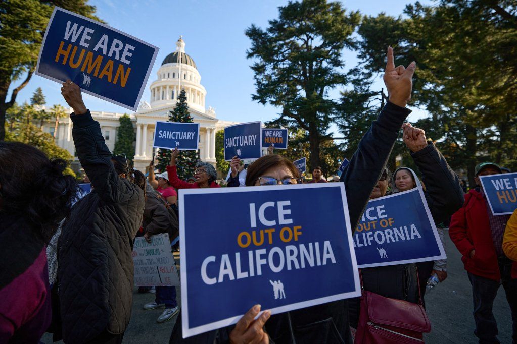 People hold up blue and white signs that read